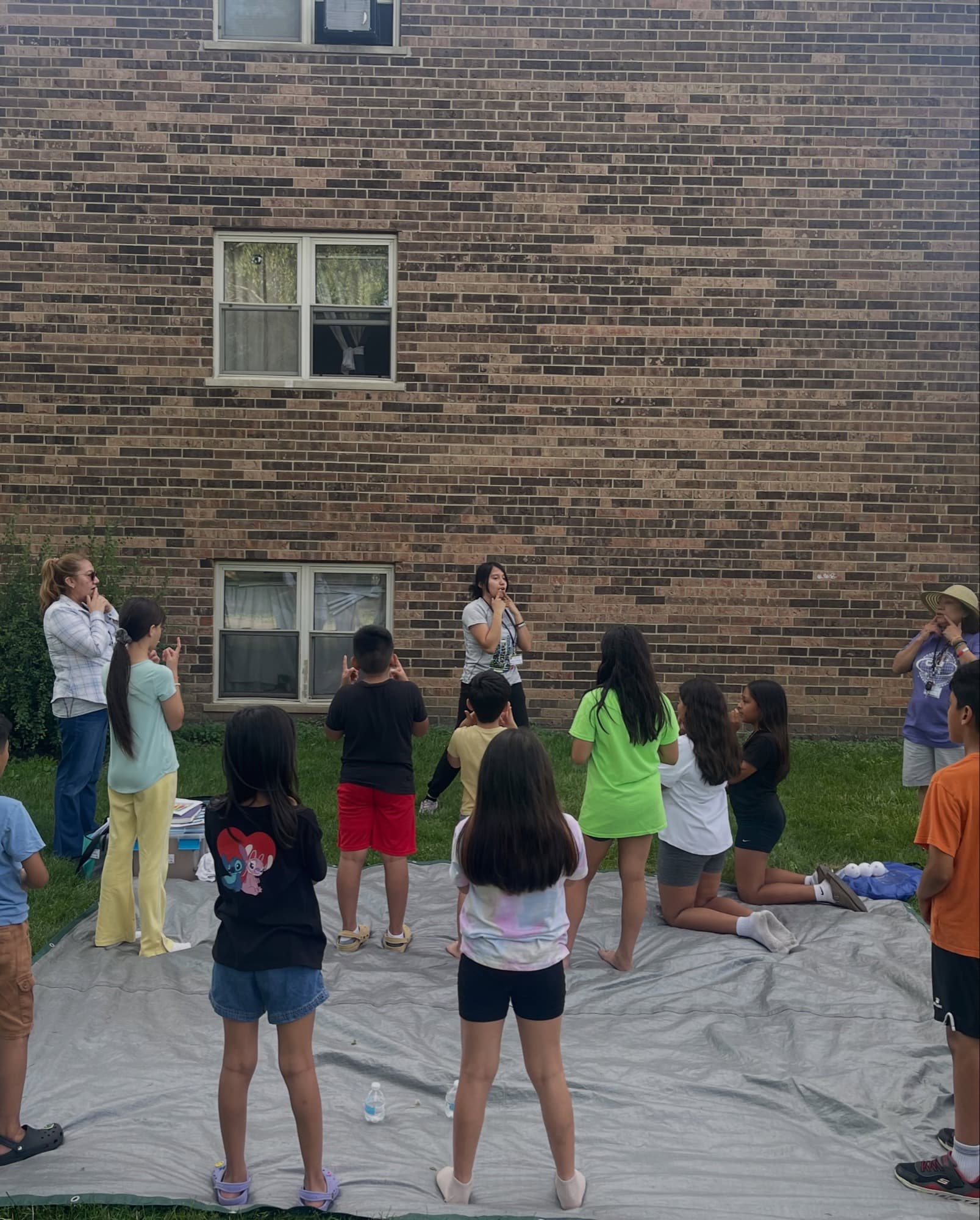 Children line up along a brick building during a game
