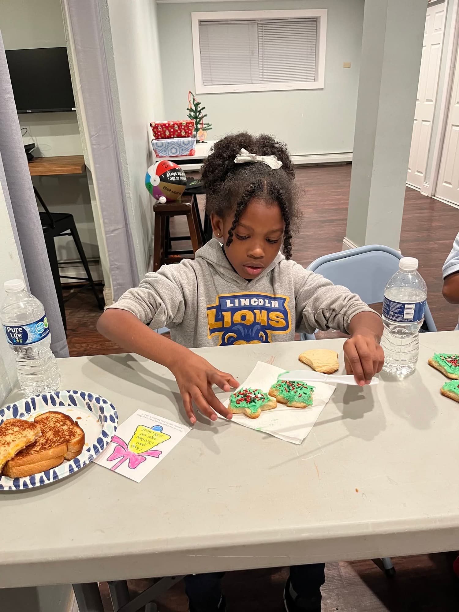 A girl decorates Christmas cookies at a table