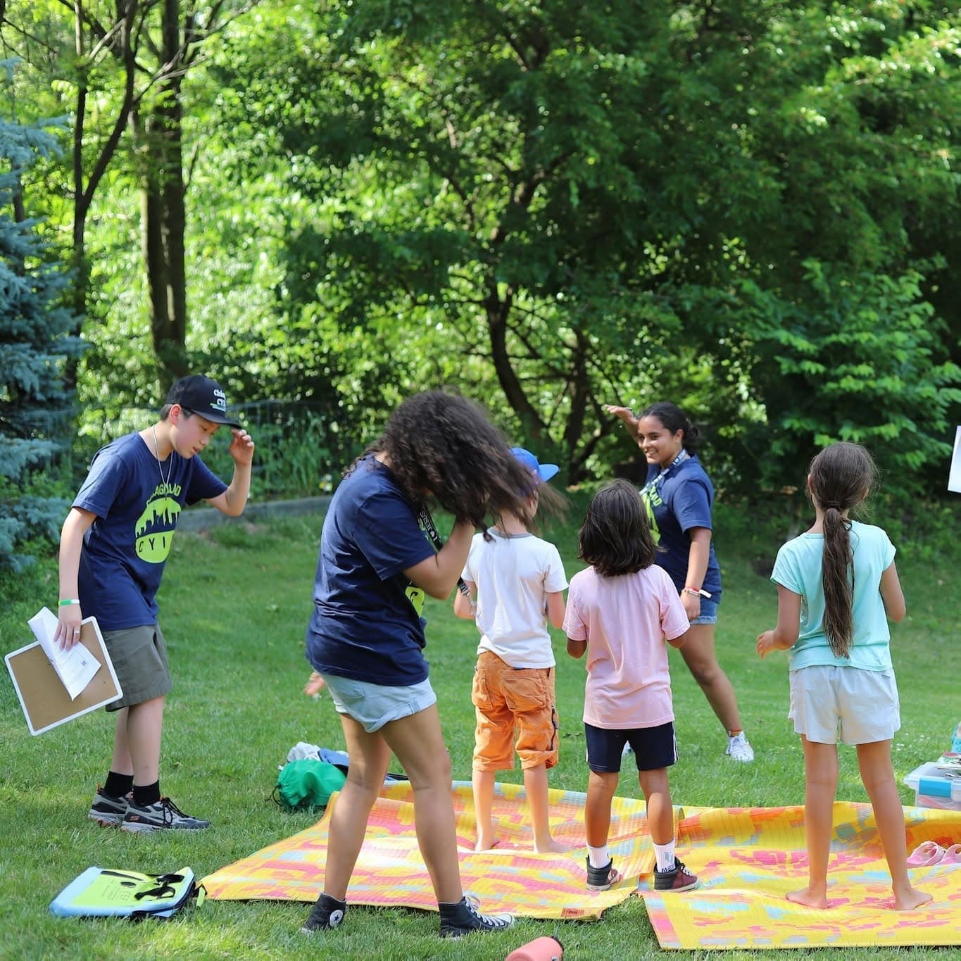Children and teenage leaders play a game on bright mats on the grass